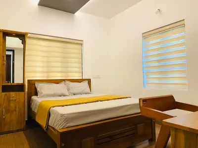 a bedroom with a bed with a window and a desk at Captain's Cove Home Stay in Sultan Bathery