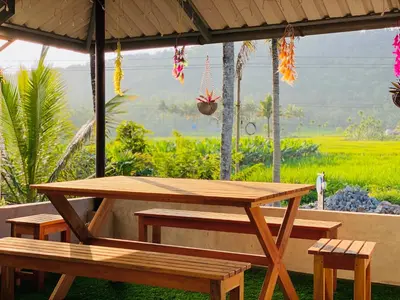 a wooden picnic table and benches under a pavilion at Captain's Cove Home Stay in Sultan Bathery