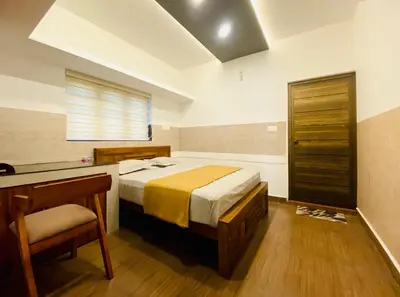 a bedroom with a bed and a desk with a chair at Captain's Cove Home Stay in Sultan Bathery