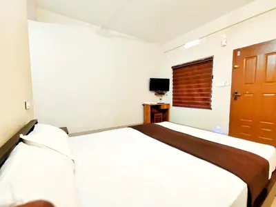 a bedroom with a white bed and a wooden door at Mizzle Resort in Padinjarathara