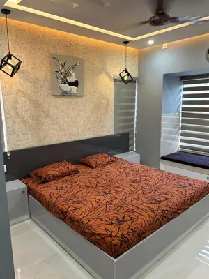 a bedroom with a bed with a orange comforter at Thottan house in Trichūr