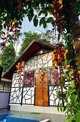 a small house with a wooden door and windows at Josh Holidays Wayanad in Vaduvanchal