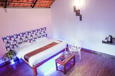 a bedroom with a bed and a table and a chair at Josh Holidays Wayanad in Vaduvanchal