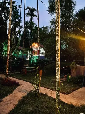 a garden with a house with a beam of light at Josh Holidays Wayanad in Vaduvanchal