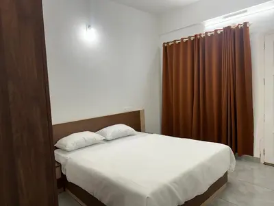 a bedroom with a bed and a brown curtain at Jayalakshmi Residency in Vaduvanchal