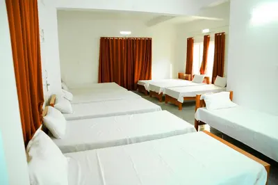 a row of beds in a room with red curtains at Jayalakshmi Residency in Vaduvanchal