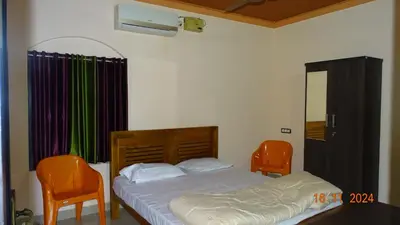 a bedroom with a bed and two orange chairs at Nirmalyam Homestay in Kuttippuram