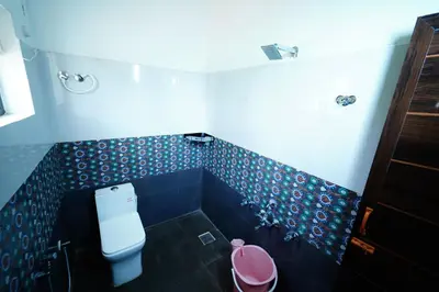 a bathroom with a toilet and blue tiled walls at Trogon resort in Kabini River
