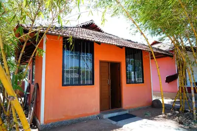 an orange house with an orange door and trees at Trogon resort in Kabini River