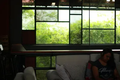 a woman sitting on a couch in front of a window at Vettaths in Kozhikode
