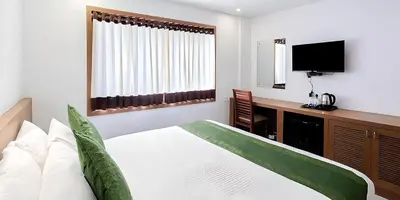 a bedroom with a bed and a desk and a television at Seaflare Beach Resort & Spa in Pallipuram