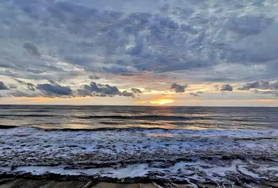 a view of the ocean with the sun setting at Seaflare Beach Resort & Spa in Pallipuram