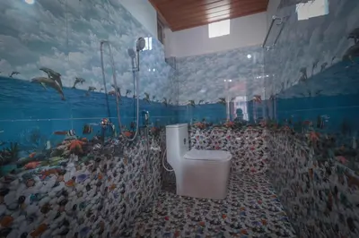 a bathroom with a fish mural on the wall at Flintstone Home in Kushālnagar