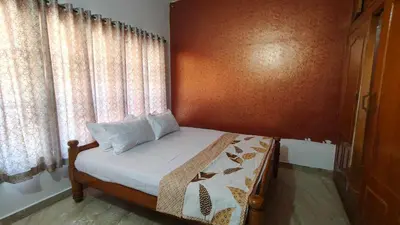 a bedroom with a bed and a window with curtains at Flintstone Home in Kushālnagar