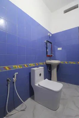 a blue bathroom with a toilet and a sink at Flintstone Home in Kushālnagar