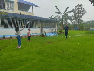 a man and two children flying a kite in a yard at Suggi Farm House in Halgūr