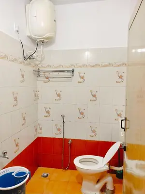a bathroom with a toilet and a red and white tiled wall at Harvest Hill View Cottage in Ooty