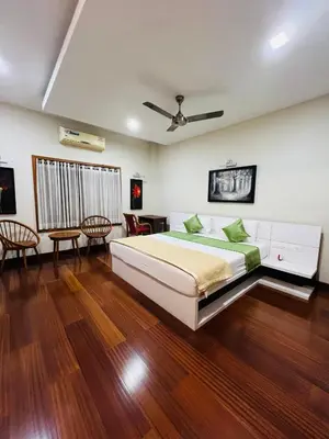 a bedroom with a large bed and wooden floors at Yemcee Rivera in Tellicherry