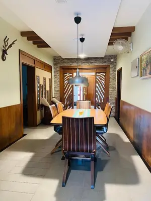 a dining room with a wooden table and chairs at Yemcee Rivera in Tellicherry
