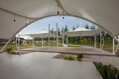a large white tent with umbrellas in a park at Encanto Farmstay Resort in Mysore