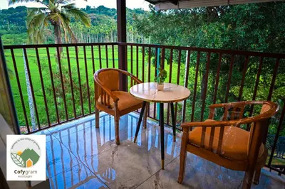a table and two chairs on a balcony with a view at Cofygram cottages in Wayanad