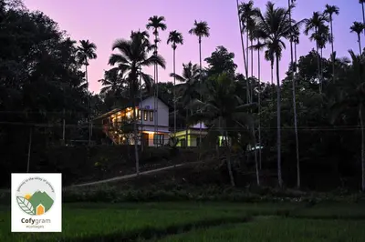 a house on a hill with palm trees at night at Cofygram cottages in Wayanad