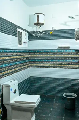 a bathroom with a toilet and a wall with stripes at Cozy Haven Homestay in Meenangadi