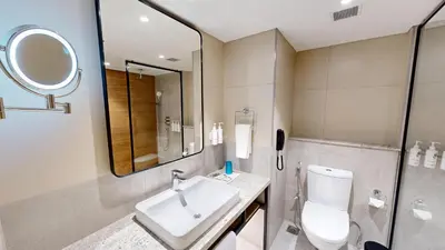a bathroom with a sink and a toilet and a mirror at Park Inn & Suites by Radisson Thrissur East Fort in Trichūr