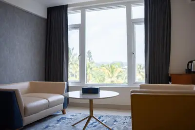 a living room with a chair and a table and a window at Mazarine Hotels & Resorts LLP in Kalpetta
