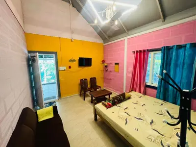 a room with a bed and a couch and a tv at LAKSHMI NIKUNj Estate Stay in Madikeri