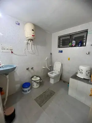 a bathroom with a white toilet and a sink at GURI Homestay in Kushālnagar