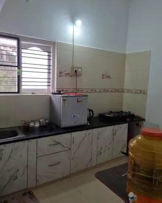 a kitchen with a stove and a counter top at GURI Homestay in Kushālnagar