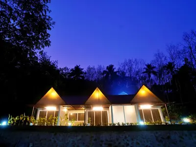 a house lit up at night with lights at Elephant Village Private Pool Villa in Munnar