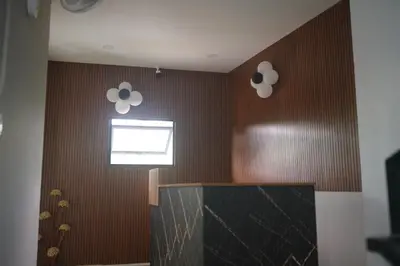 a bathroom with brown walls with a window and two lights at Cruz Inn calicut in Kozhikode