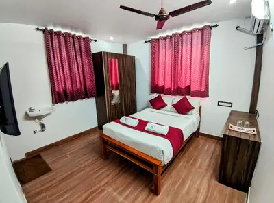a bedroom with a bed with red curtains and a tv at Skyry Hotels Singanallur in Coimbatore