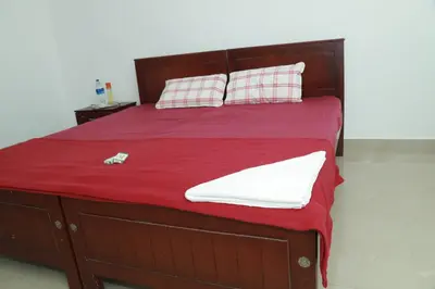 a bed with red sheets and pillows and a red blanket at Royal Park in Wayanad