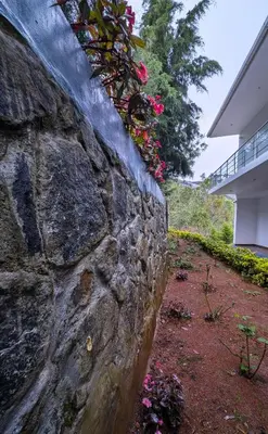 a stone wall with flowers on it next to a building at VALLEY VIEW INN, Kotagiri in Kotagiri