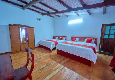 a bedroom with two beds and a chair at Shivvs Heritage Resort Ooty in Ooty