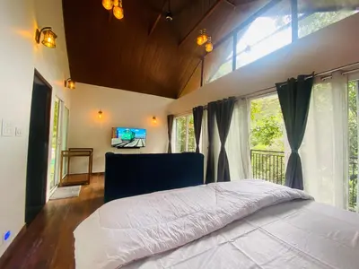 a bedroom with a large bed and a tv at SR Villa - Serenity by riverside in Meppādi