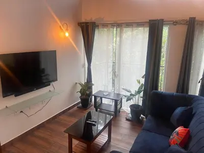 a living room with a couch and a flat screen tv at SR Villa - Serenity by riverside in Meppādi