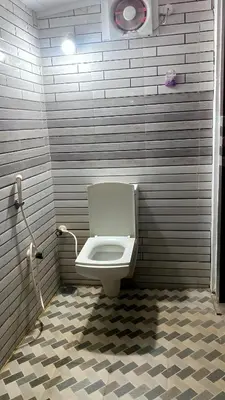 a bathroom with a white toilet in a stall at The Rain Tree resort in Kutta