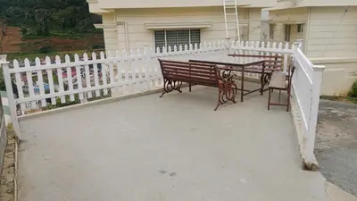 a bench and a table in front of a white fence at The silver dale homestay 1 in Ooty