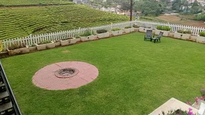 a lawn with two chairs and a white fence at The silver dale homestay 1 in Ooty