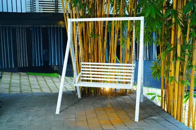 a white bench sitting next to a wall with bamboo at Palatty's Resorts in Athirappally