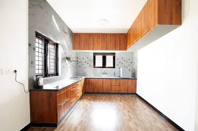 a kitchen with wooden cabinets and a wooden floor at Haven inn in Kotagiri