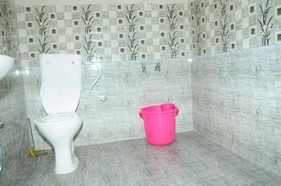 a bathroom with a toilet and a pink bucket at Bethany stay in Ooty
