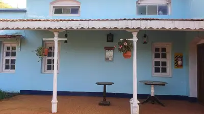 a blue house with two stools in front of it at Cliff Club Resort Ooty in Ooty