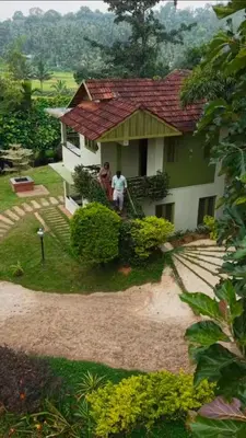 two people are standing outside of a house at Ayurnest Pool Resort Wayanad in Batheri