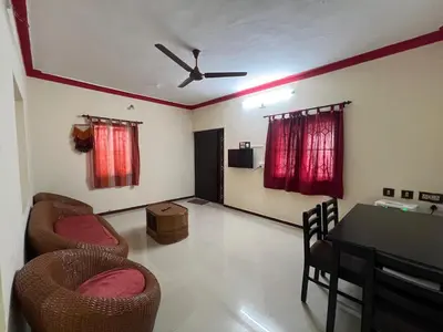 a living room with chairs and a table and red curtains at SHI's 2bhk Near Ganga Hospital in Coimbatore