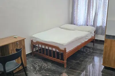 a small bed in a room with a table and a chair at Entire 4 Bedroom Villa in Kannur in Edakkād